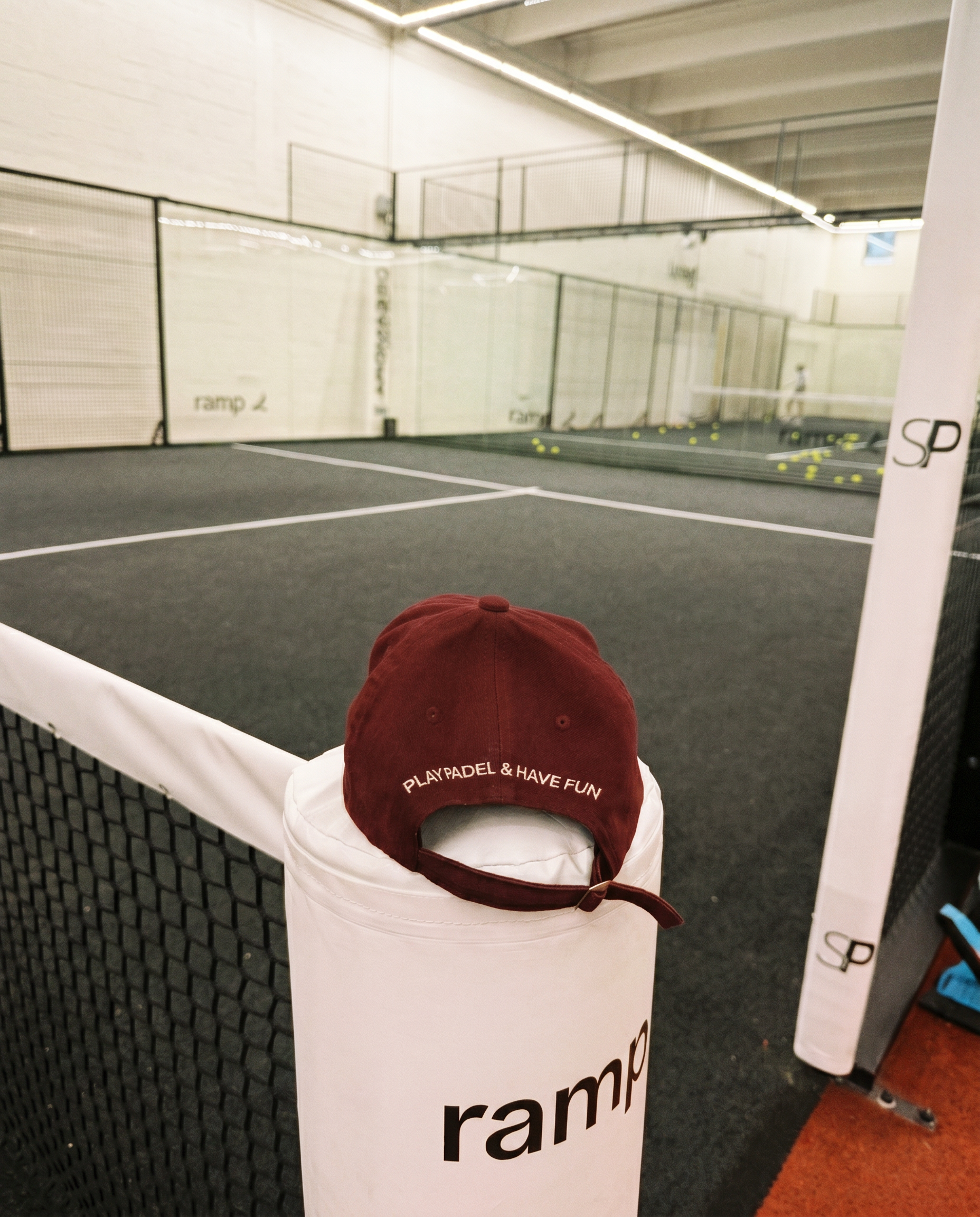 Maroon cap on a white padel court post with indoor court in the background