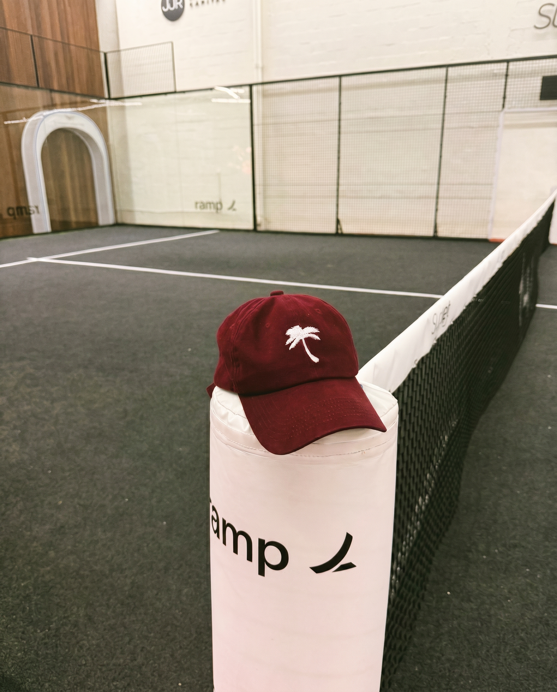Red cap with a palm tree logo on a white pole in an indoor sports facility.