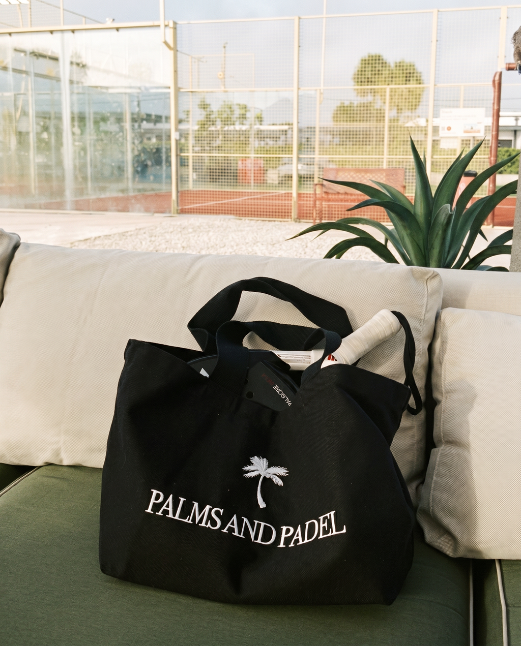 Black bag with 'Palms and Padel' logo on a couch outdoors